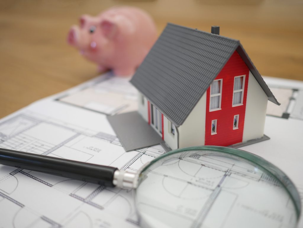 Document with a magnifying glass, house, and piggy bank.